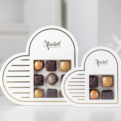 Elegant hvid hjerteformet æske med gyldne detaljer, fyldt med 9 håndlavede chokolader i smagsvarianterne nougat, marcipan, flødekaramel og saltkaramel – en perfekt lille gave til en, du holder af.