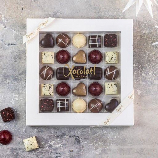 Elegant æske fra Christiansfelder Star-serien med 25 fyldte chokolader i forskellige smagsvarianter som marcipan, hasselnød, citron, lakrids, romkaramel, appelsin, kirsebærmarcipan, kahlua og saltkaramel – en luksuriøs gaveæske med håndlavet chokolade