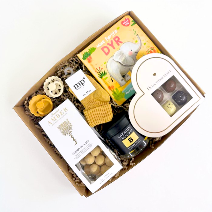 Sød gul barselsgave med bog, strømper, sutter, lakrids og chokolade.