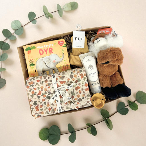 Sød gaveløsning med krammebamse, bog og andre sager til baby